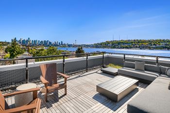 a rooftop deck with furniture and a view of the city